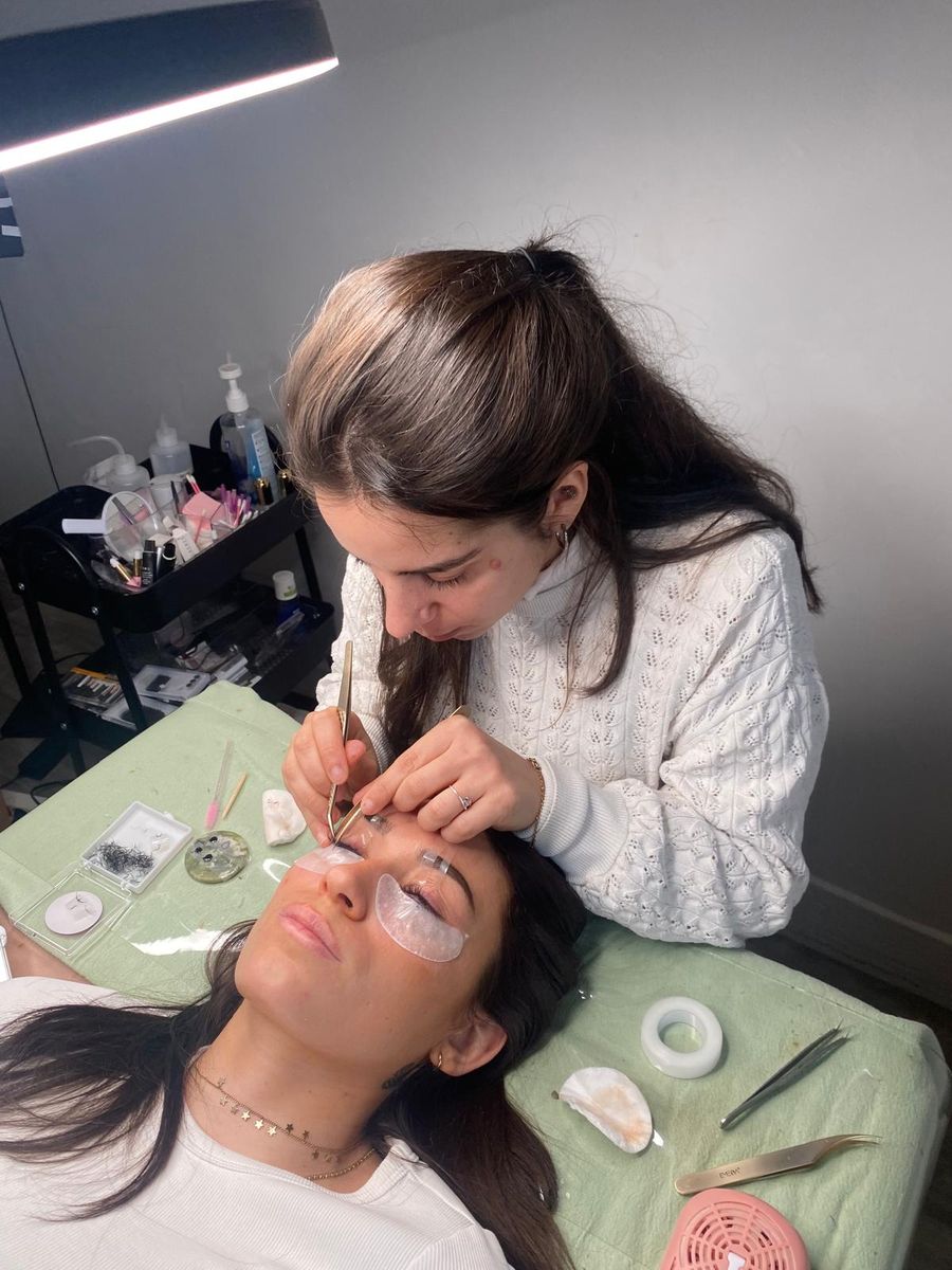 Camille réalisant une pose de cils à l'atelier